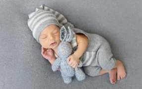 Спящий младенец с серым вязаным зайцем