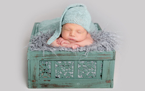 A sleeping child in a green box on a gray background