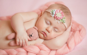 A sleeping little girl with a crocheted teddy bear in her hand