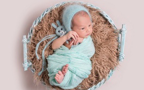 Маленький ребенок в корзине на сером фоне