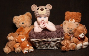 Маленький ребенок в вязанной шапке с  игрушечными медвежатами 