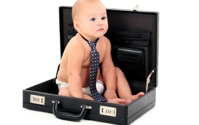 Маленький ребенок в галстуки сидит в кожаном дипломате