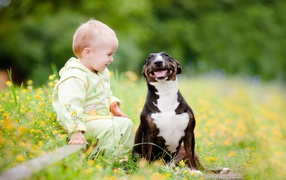 A small child is sitting with a satisfied dog.