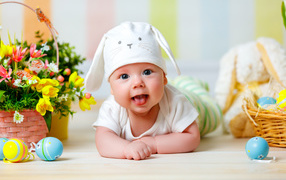 Маленький ребенок с корзиной цветов и пасхальными яйцами