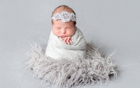 Маленький спящий младенец на сером фоне