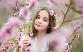 Красивая кареглазая девочка с розовыми цветами на дереве