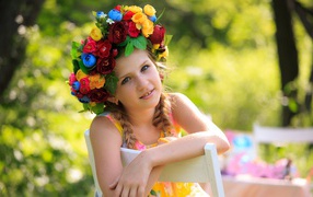 Beautiful girl with a wreath on her head sitting on a chair