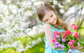Красивая маленькая девочка с букетом тюльпанов весной
