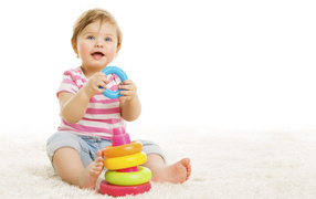 Голубоглазый маленький мальчик с игрушкой на белом фоне