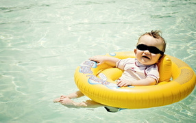Веселый малыш на спасательном кругу в бассейне