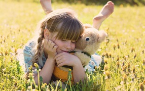 Девочка лежит на траве с игрушкой