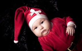 Грудной ребенок в красном новогоднем костюме