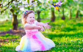 Laughing little girl in beautiful dress on green grass