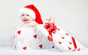 Маленький ребенок в новогоднем костюме в коробке для подарка на сером фоне