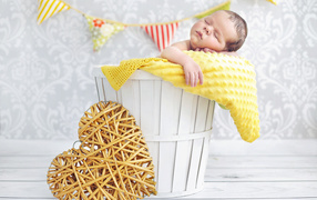 Маленький ребенок спит в корзине с плетеным сердцем