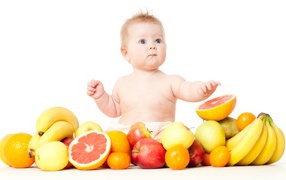 Little blue-eyed baby with fruit on a white background