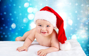 Маленький голубоглазый ребенок в красном новогоднем колпаке