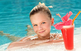 Маленькая голубоглазая девочка в бассейне с коктейлем