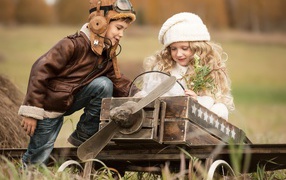 Маленькие мальчик и девочка в игрушечном самолете