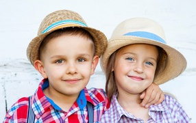 Маленькие мальчик и девочка в соломенных шляпах на пляже