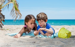Маленькие мальчик и девочка играют на песке на пляже