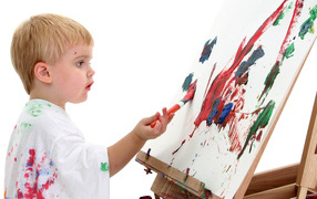 Маленький мальчик рисует красками 