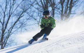 Маленький мальчик спускается с горы на лыжах