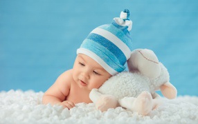 Маленький мальчик в голубой шапке с игрушкой 