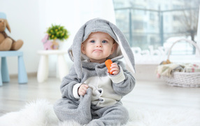 Little boy in a bunny costume with a carrot in his hand
