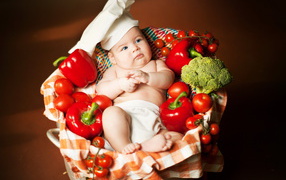 Маленький мальчик в костюме повара в корзине с перцем и помидорами