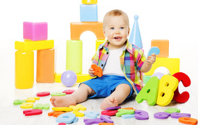 Маленький мальчик играет с разноцветными игрушками 