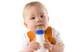Маленький мальчик с бутылкой молока на белом фоне