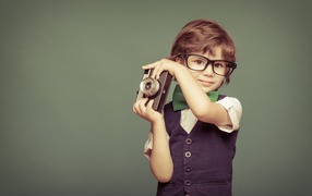 Маленький мальчик в очках с фотоаппаратом