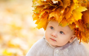 Little cute baby with a wreath of yellow leaves on her head