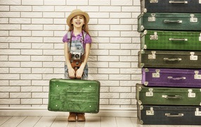 Little girl at the wall with big suitcases