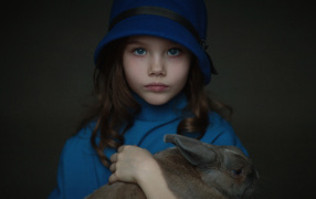 Little girl in a blue hat with a rabbit