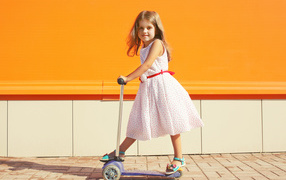 Little girl in a dress on a scooter
