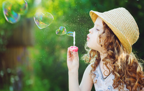 Little girl in a hat with soap bubbles