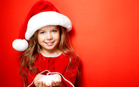 Маленькая девочка в новогодней шапке на красном фоне