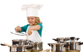 Маленькая девочка в костюме повара на кухне