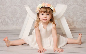 Маленькая девочка сидит на шпагате