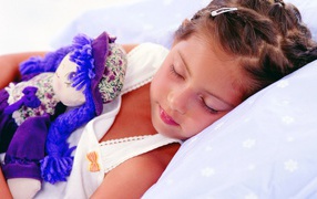 Маленькая девочка спит с игрушкой