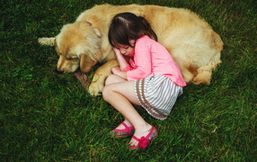Маленькая девочка спит на зеленой траве с собакой