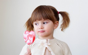 Маленькая девочка с большой конфетой на палочке