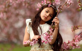 Маленькая девочка у цветущей розовыми цветами ветки