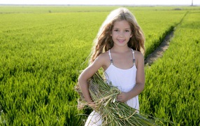 Маленькая девочка с травой в руках на поле
