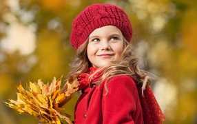 Маленькая девочка с желтыми листьями в руке осенью