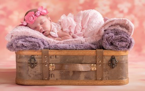 Little newborn girl sleeping on a suitcase