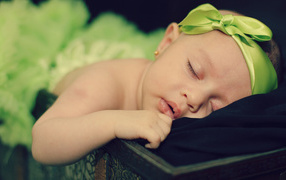 Маленькая спящая девочка с ленточкой на голове