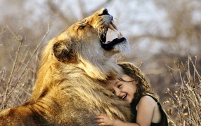 Маленькая улыбающаяся девочка обнимает льва